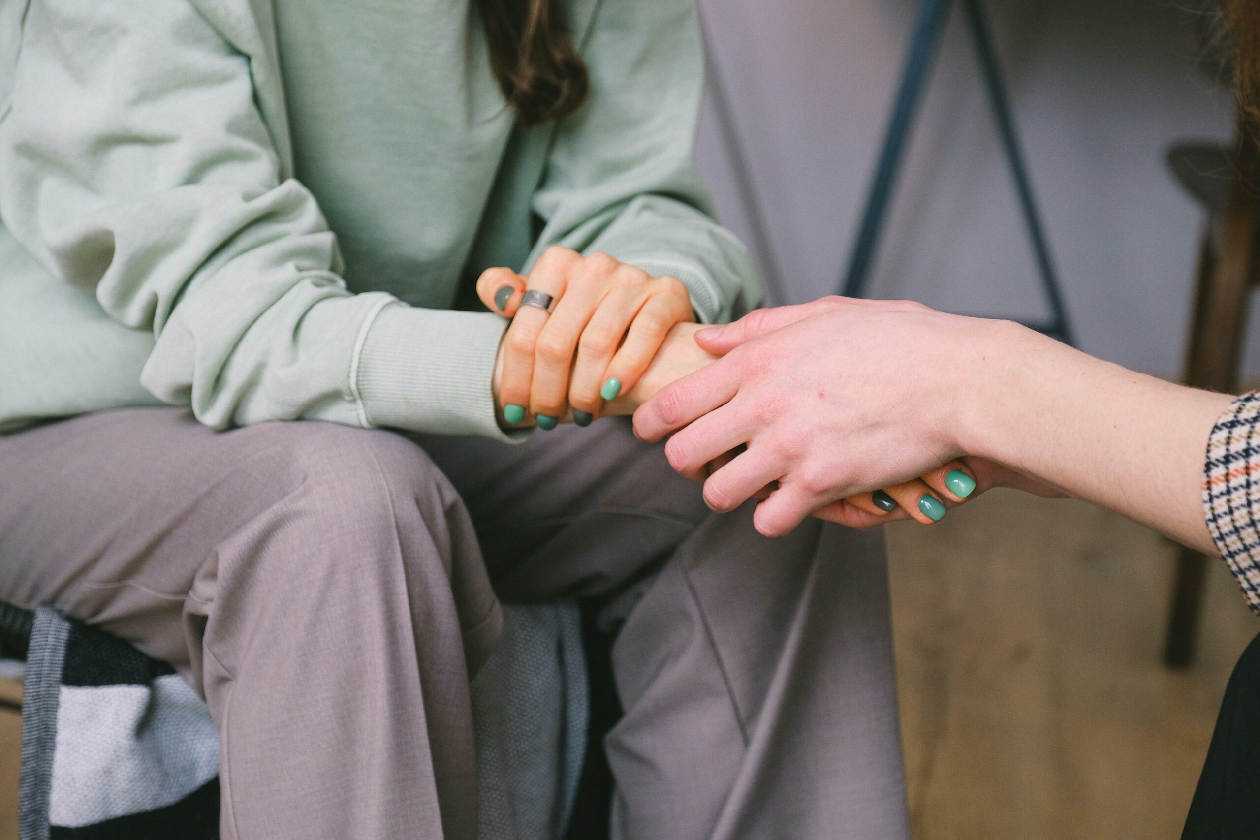 Close-up of two people holding hands during a comforting therapy session.